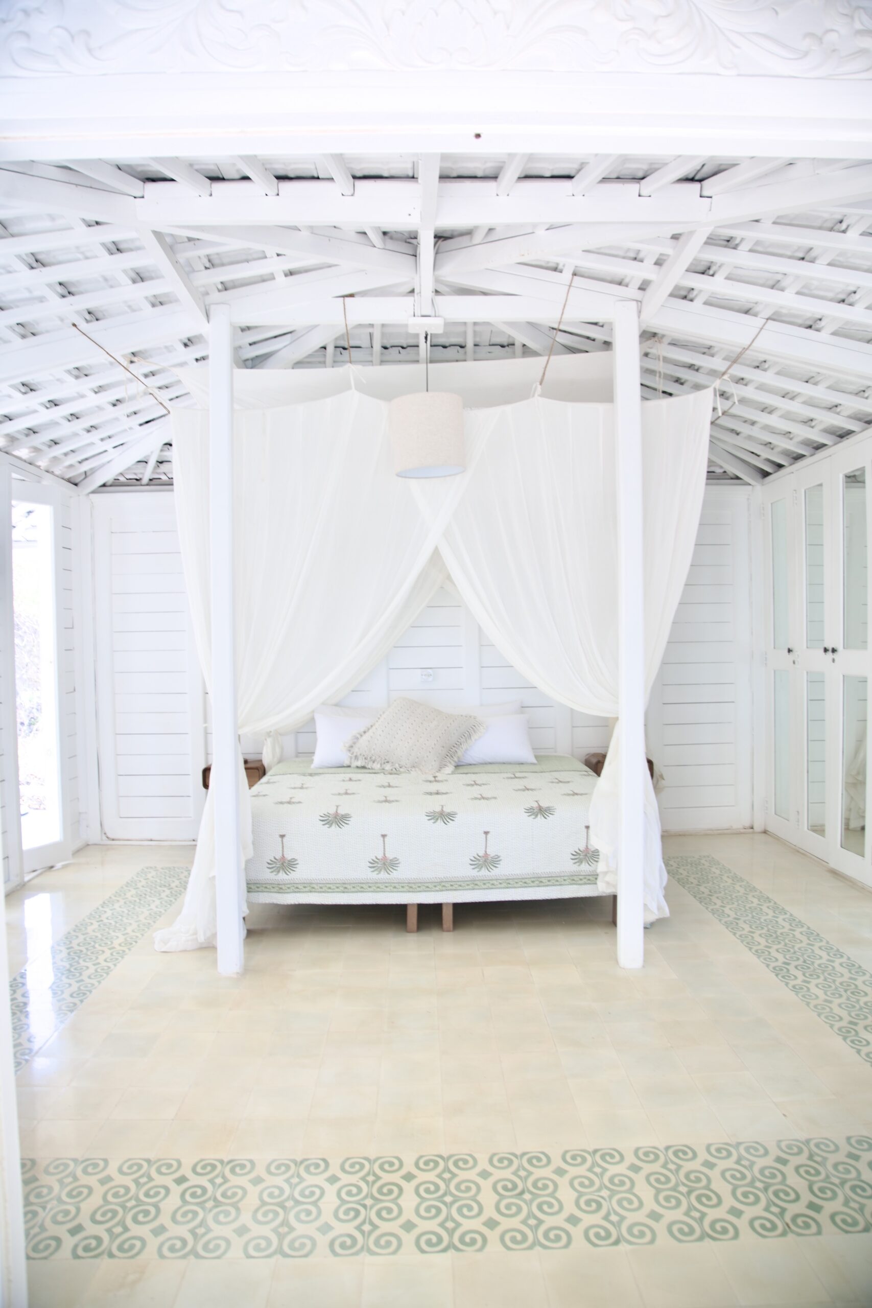 Airy white interior of a Bungalow with a canopied bed and soft natural light