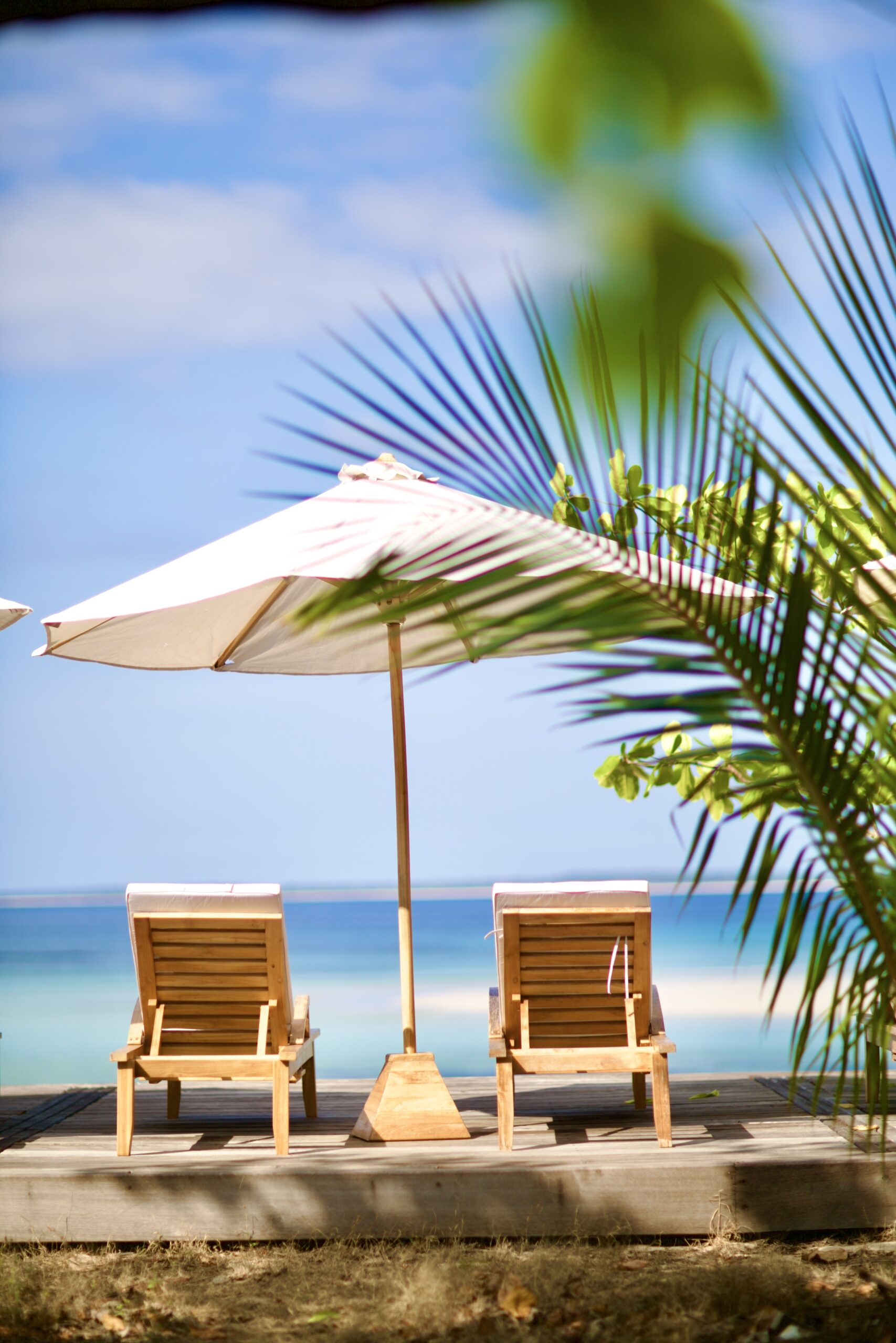 A parasol and lounger looking out over the turquoise lagoon and a distant island